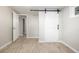 Bright bedroom with a sliding barn door, light grey walls, and light wood-look flooring at 2260 S Lewiston St, Aurora, CO 80013
