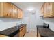 Galley kitchen with efficient stainless steel appliances, wood cabinetry, and a tiled floor at 10211 Ura Ln # 2-207, Thornton, CO 80260