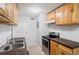 Galley kitchen featuring updated stainless steel appliances, a tiled floor, and wood cabinetry at 10211 Ura Ln # 2-207, Thornton, CO 80260