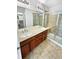 Bathroom featuring a double sink vanity, tiled floors, and a glass-enclosed shower for a functional and stylish space at 25952 E 5Th Pl, Aurora, CO 80018