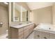 Bathroom featuring double sinks, vanity, a tub with tile trim, and bright lighting at 1060 S Eaton St, Lakewood, CO 80226
