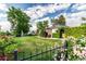 A beautiful yard featuring a well-kept lawn, mature trees, decorative fence and manicured greenery surrounding the home at 1060 S Eaton St, Lakewood, CO 80226