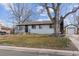 Inviting home exterior with white brick, black trim, mature tree, and detached garage at 5060 S Fox St, Englewood, CO 80110