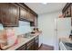 Compact kitchen featuring stainless sink, dark wood cabinetry, and white appliances at 384 S Ironton St # 201, Aurora, CO 80012
