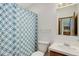 This cozy bathroom features a blue and white patterned shower curtain, toilet, sink, and vanity at 8481 Uinta St, Commerce City, CO 80022