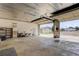 Spacious garage interior with a large open area, a storage shelf, and a view to the outdoors at 8481 Uinta St, Commerce City, CO 80022
