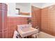 Retro bathroom with pink tiling, a unique sink fixture, and classic design elements at 6110 E 6Th Avenue Pkwy, Denver, CO 80220