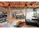 Open living space with modern kitchen, dining area, and living room with exposed brick and wood beam ceilings at 2955 Inca St # 2D, Denver, CO 80202