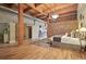 Open concept main bedroom featuring wood floors, brick accent wall, and ensuite bathroom at 2955 Inca St # 2D, Denver, CO 80202
