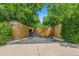 Exterior view of the property showcasing a gated driveway, fence, and lush greenery at 6505 W Hampden Ave, Lakewood, CO 80227