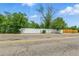 View of the exterior property with a long white fence and greenery at 6505 W Hampden Ave, Lakewood, CO 80227