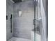 Sleek walk-in shower featuring gray tiling, a rain shower head, and pebble tile flooring at 6505 W Hampden Ave, Lakewood, CO 80227