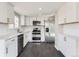 Modern kitchen with white cabinetry, stainless steel appliances, quartz countertops, and dark hardwood floors at 5153 Scranton St, Denver, CO 80239