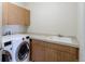 Functional laundry room with cabinetry, sink, and modern washer and dryer units at 14033 E Whitaker Dr, Aurora, CO 80015