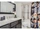 Elegant bathroom featuring marble countertops, stylish fixtures, and tiled shower-tub with a decorative curtain at 9523 Sherrelwood Ln, Highlands Ranch, CO 80126