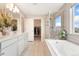 Bright bathroom featuring double vanity, soaking tub with shower, and a view of a walk in closet and neighborhood at 19121 E 65Th Ave, Denver, CO 80249