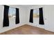 A simplistic bedroom with hardwood flooring, black-out curtains, and bright white walls at 575 2Nd St, Bennett, CO 80102