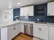 Modern kitchen features bright white cabinetry, a marble countertop, stainless steel appliances, and a blue accent wall at 575 2Nd St, Bennett, CO 80102