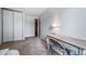 Neutral bedroom with a side table desk with lamp plus closet doors and door leading to hallway at 10007 Bryant St, Denver, CO 80260
