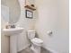 Compact powder room features a pedestal sink and a decorative round mirror at 4862 S Piccadilly Ct, Aurora, CO 80015