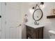 Stylish half bath featuring modern fixtures, a rustic vanity, and round mirror at 5648 S Youngfield Way, Littleton, CO 80127