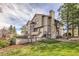 Exterior view of home showcasing a stone chimney, multi-level deck, and lush landscaping at 187 W Prestwick Ct, Castle Rock, CO 80104