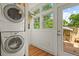 Laundry room with stacked washer and dryer, bright sunlight, and hardwood floors at 2716 N Vine St, Denver, CO 80205