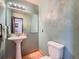 A green-themed bathroom featuring a pedestal sink, toilet, and large mirror at 4032 S Atchison Way, Aurora, CO 80014
