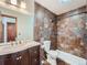 A tiled bathroom with a modern vanity, decorative mirror and combination shower-tub at 4032 S Atchison Way, Aurora, CO 80014