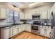 Well-lit kitchen boasts white cabinets, stainless steel appliances, sleek countertops and hardwood floors at 8834 Blue Mountain Pl, Highlands Ranch, CO 80126