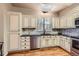 Bright kitchen featuring white cabinets, stylish countertops, stainless steel appliances, and a skylight at 8834 Blue Mountain Pl, Highlands Ranch, CO 80126
