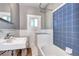Cozy bathroom with blue tiling, a tub, a window for natural light, and a white vanity at 3336 N Saint Paul St, Denver, CO 80205