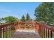 Outdoor deck with red painted wood railing overlooking mature trees and a clear blue sky at 4064 S Himalaya Way, Aurora, CO 80013