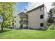 Apartment building exterior with balconies, grassy lawn, and mature trees at 6505 Kalua Rd # 104B, Boulder, CO 80301