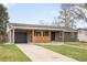 Charming home featuring a covered porch, a dark gray garage door, and a well-manicured lawn at 815 S Jersey St, Denver, CO 80224