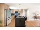 A modern kitchen featuring wood cabinets, stainless appliances, blue backsplash, and a large island with barstool seating at 815 S Jersey St, Denver, CO 80224