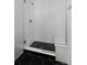 Clean and modern shower with glass door, white tile, and black and white tile floors at 10860 Lyric St, Lone Tree, CO 80134