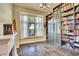 A lovely office with dark hardwood floors, library-style bookshelves, a fireplace and natural light from the window at 11881 County Road 37, Fort Lupton, CO 80621