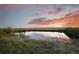 Scenic pond view reflecting the colorful sunset sky, surrounded by lush greenery at 11881 County Road 37, Fort Lupton, CO 80621