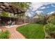 Backyard with brick path, covered patio, and well-maintained lawn at 4528 W 34Th Ave, Denver, CO 80212