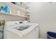 Clean laundry room featuring modern washer and dryer units with white shelving at 1462 Marigold Dr, Lafayette, CO 80026
