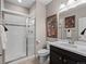 Bathroom featuring a glass enclosed shower, vanity with dark cabinets, and neutral tiling at 17077 E 111Th Ave, Commerce City, CO 80022