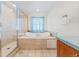 Bright bathroom features a soaking tub, tiled shower with glass door, and tile flooring at 8022 S Jay Dr, Littleton, CO 80128