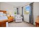 Bright bedroom featuring a comfy chair, carpet, and window with floral curtains at 8022 S Jay Dr, Littleton, CO 80128