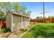 Wooden shed with light trim and double doors in a spacious, grassy backyard at 8022 S Jay Dr, Littleton, CO 80128