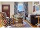 Comfortable living room featuring hardwood floors, a cozy seating arrangement, and floral curtains at 202 Lower Glenway St, Palmer Lake, CO 80133