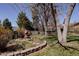 Landscaped backyard features a rock water feature, a brick-lined garden, mature trees and a wooden fence at 2415 Urban St, Lakewood, CO 80215