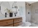 Modern bathroom featuring double sinks, wood vanity, and a walk-in shower with stone floor at 2415 Urban St, Lakewood, CO 80215