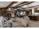 Spacious living room featuring a stone fireplace, wood paneling and exposed wood beams, plus modern decor at 2415 Urban St, Lakewood, CO 80215