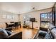 Inviting living room featuring a dining area, hardwood floors, large windows, and stylish, comfortable leather sofas at 7146 Jennie Dr, Denver, CO 80221